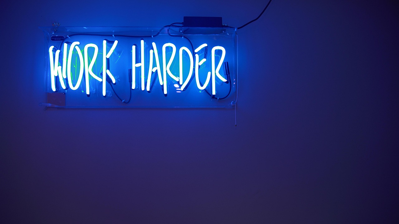 Strakke neons boven een houten tafellandschap.